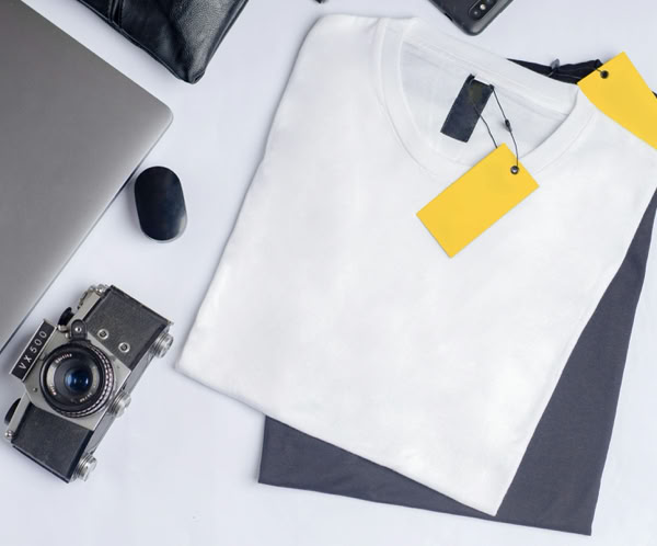 Stylish flat lay featuring a vintage camera, clothing, and laptop on a clean white background.